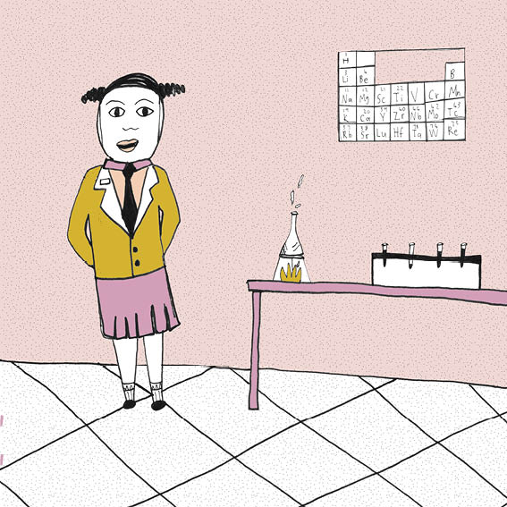 Bassie stands in a science classroom in her school uniform. She wears a head girl badge.